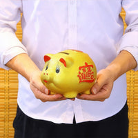 Thumbnail for Tirelire cochon porte-bonheur chinois dorée tenue en main pour montrer sa taille.