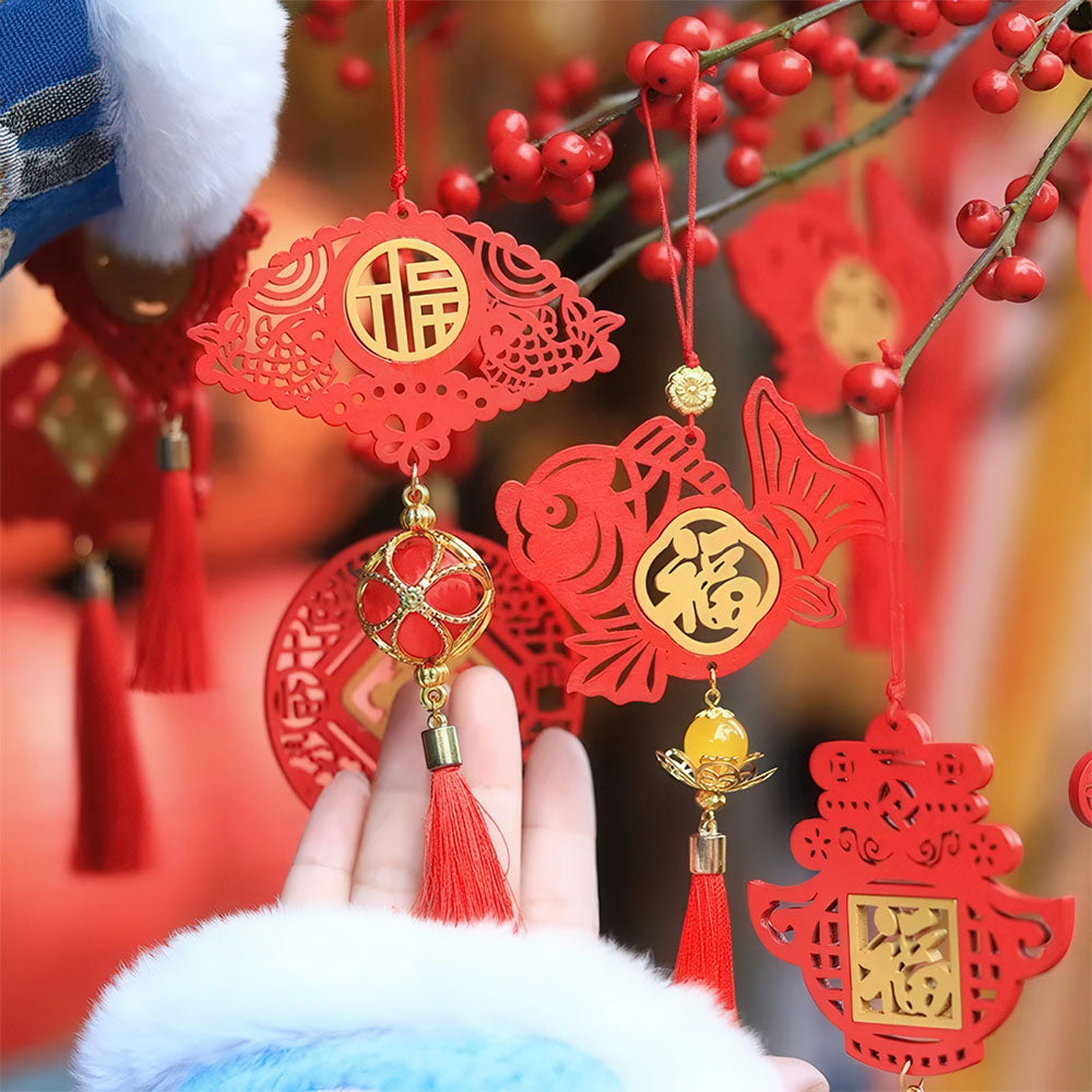 Une main présentant les pendentifs porte-bonheur en bois rouge dans une ambiance festive.