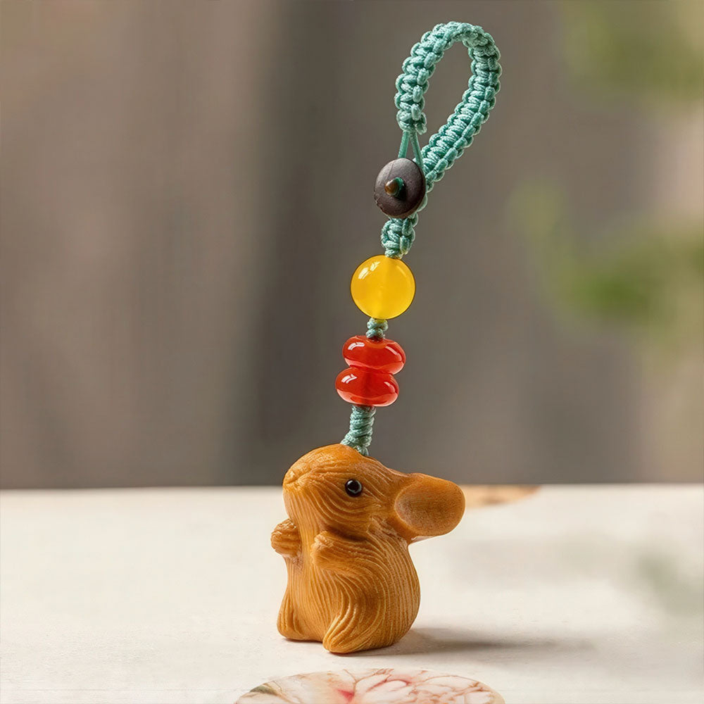 Le porte-bonheur lapin en bois clair avec sa boucle tressée et ses perles d'agate rouge.