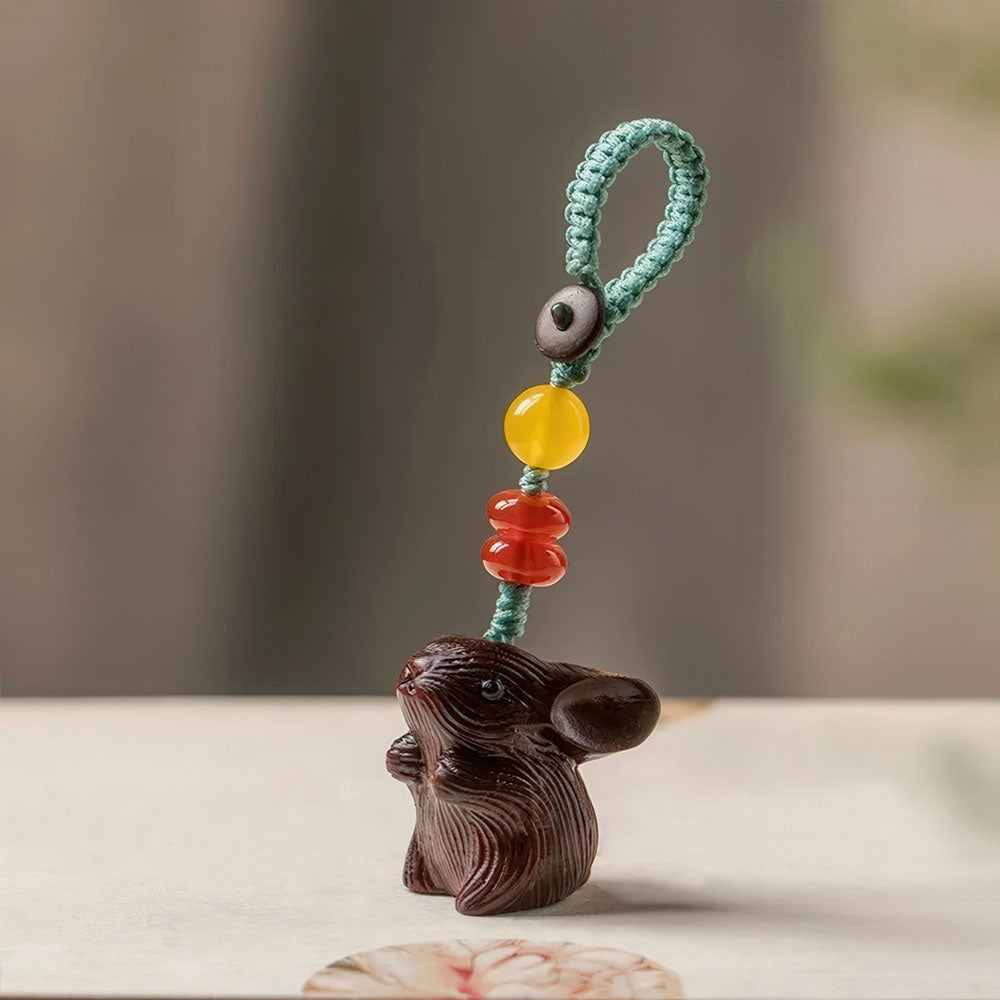 Le porte-bonheur lapin en bois foncé avec sa boucle tressée et ses perles colorées.