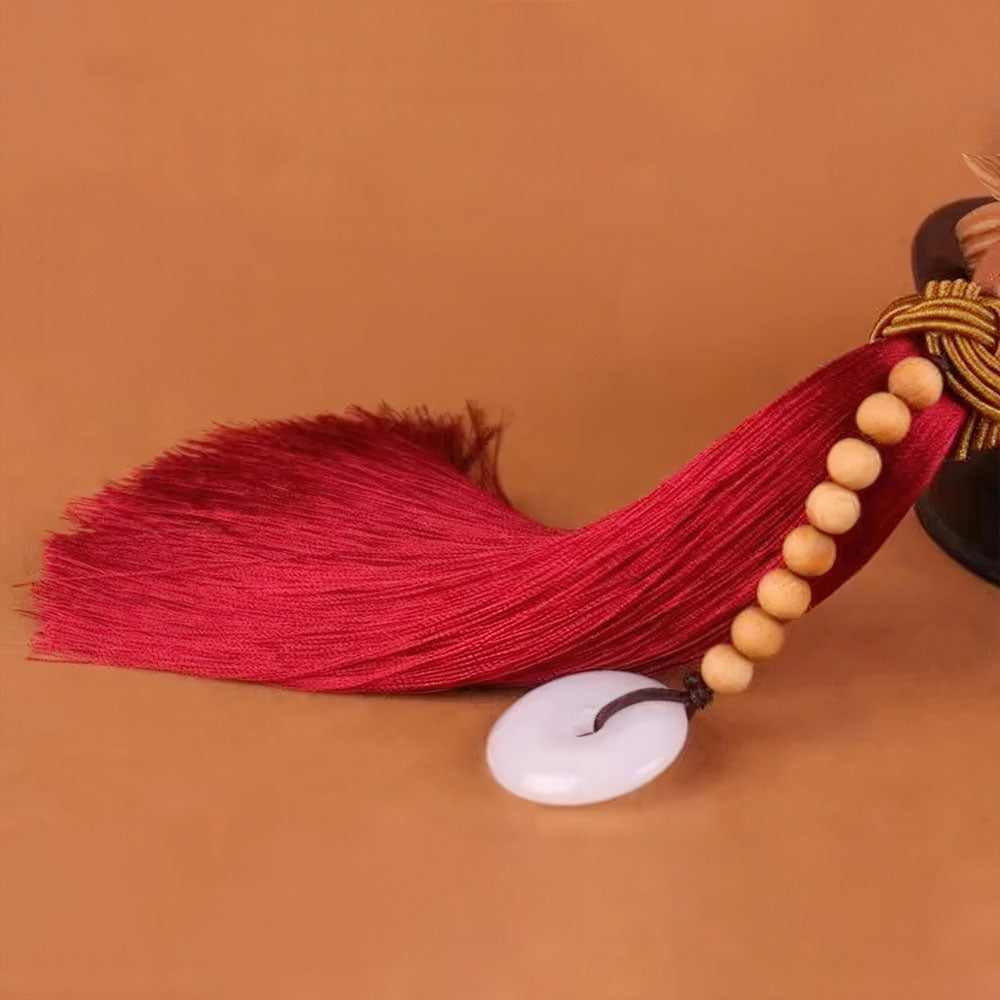 Détail du pompon avec son chapelet de perles et son disque de jade.