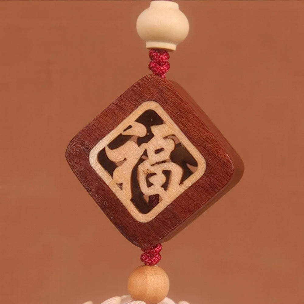 Gros plan sur le symbole "Fú" (Bonheur) en bois du porte-bonheur chinois pour voiture.