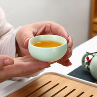 Thumbnail for Tasse du service à thé en porcelaine ancienne tenue en main, couleur céladon.