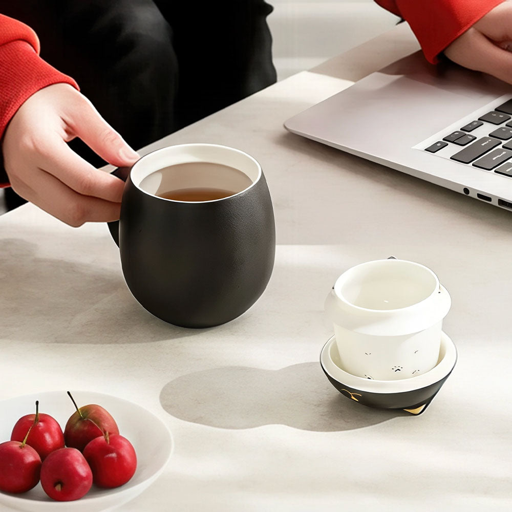 Tasse chinoise chat en céramique noire utilisée sur un bureau avec son infuseur et son couvercle