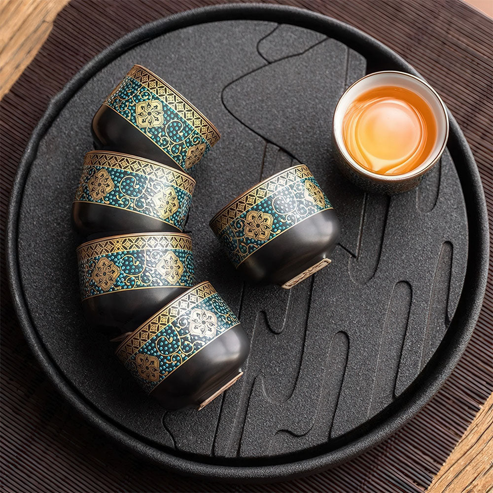 Set de tasses chinoises en porcelaine dorée disposé sur un plateau à thé noir